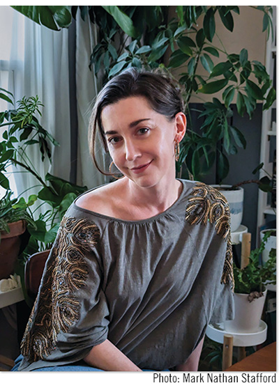 warm portrait of Rebecca Stafford inside by window surrounded by plants